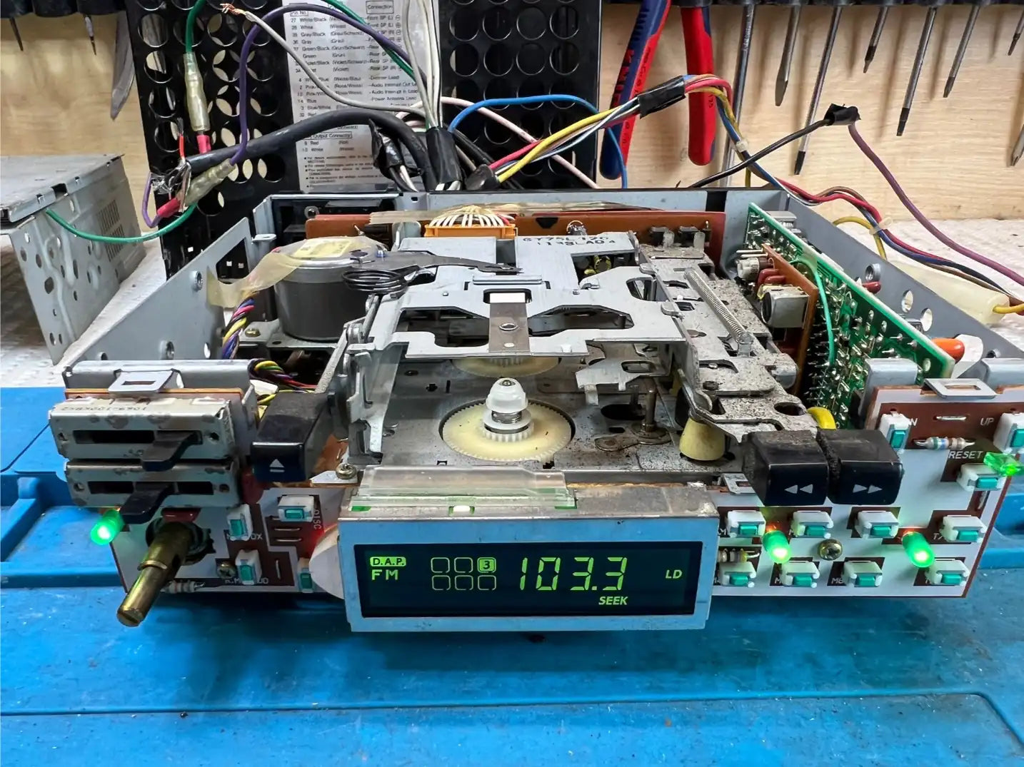 Alpine 7292MS powered on during bench testing with unit open – front board connected, buttons lit, FM display working after service and backlight work.