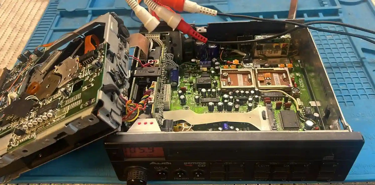 Audi Gamma car radio opened during repair showing internal circuit boards, cd mechanism and audio components

