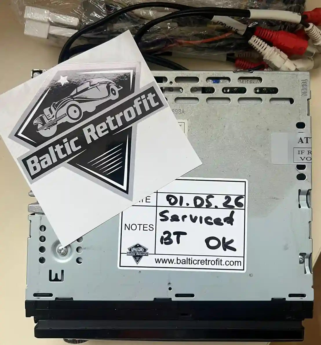 Car radio after servicing and Bluetooth retrofit with service label confirming testing and functionality
