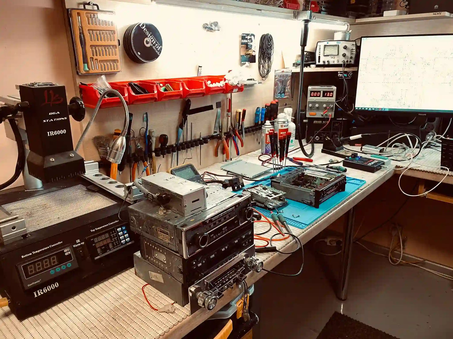 Vintage car radio repair workshop with electronic test equipment, tools and radios under service